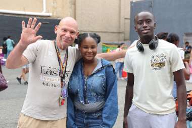 Volunteers and a young neighbor smiling together at the Back to School Outreach in Newark